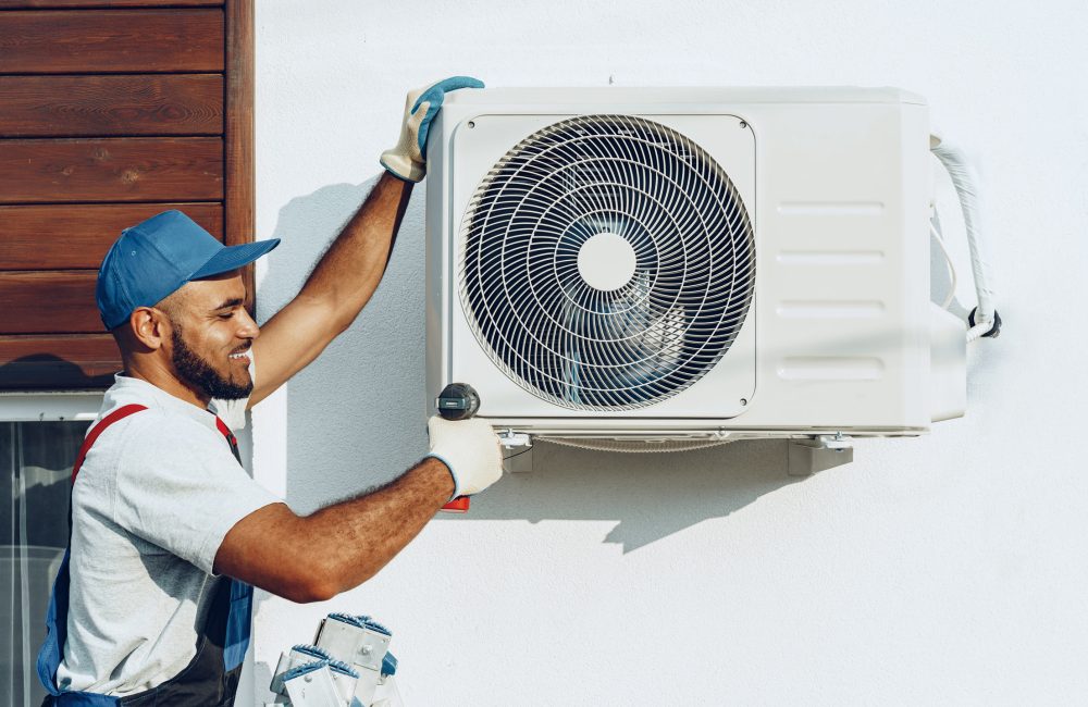 Technician mounting outdoor mini-split AC unit on Calgary home exterior wall – Shift Heating and Cooling Services