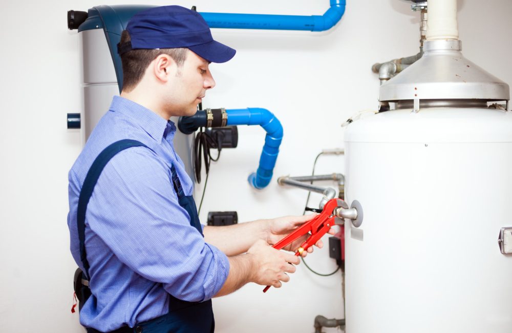 Calgary plumber repairing residential hot water tank with red pipe wrench – Shift Heating and Cooling Services